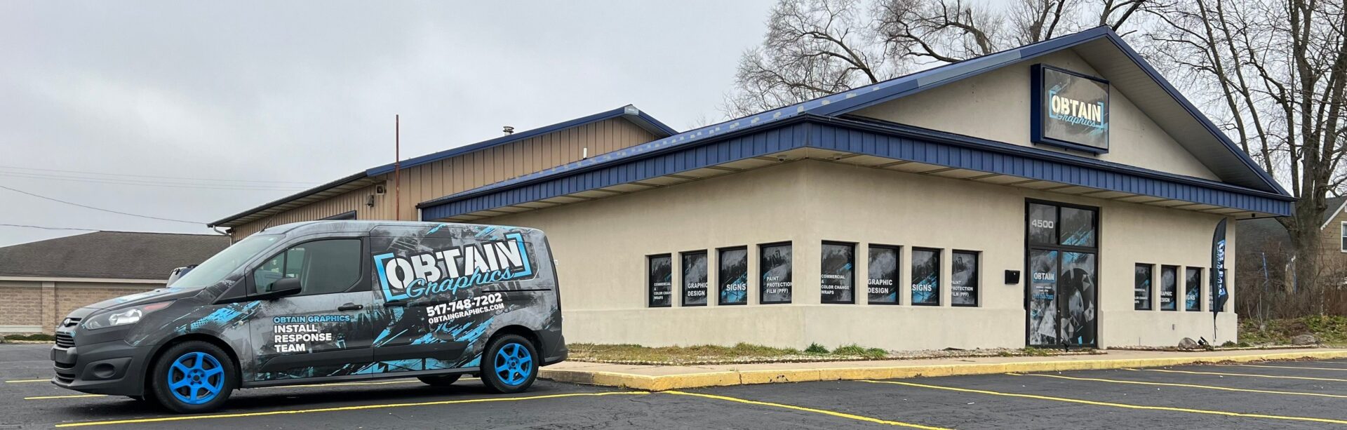 A van parked in front of a building with blue windows.