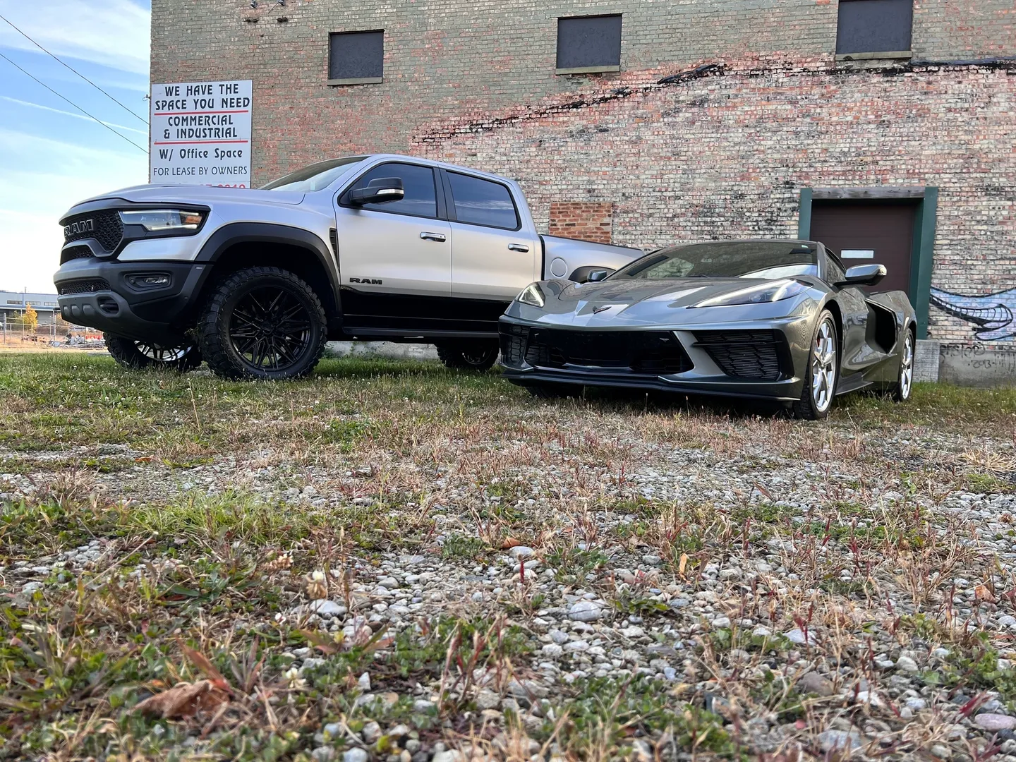 A silver truck parked next to a black sports car.